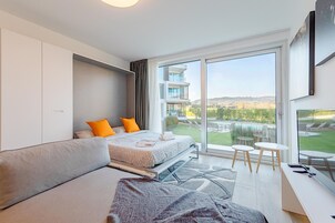Una camera d'albergo moderna con un letto grande, un divano, una scrivania e un balcone con vista sulla piscina.