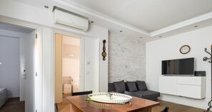 A modern living room with a dining table, sofa, and TV.
