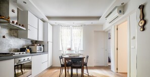 A modern kitchen with a dining area, featuring a stove, microwave, and a dining table with chairs. - XVI Charm Apartment by Wonderful Italy (Bologna)