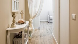 A narrow hallway with a white table, a white chair, and a wicker basket.