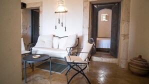 Une pièce chaleureuse avec un canapé blanc, deux fauteuils, une petite table ronde et une décoration murale.