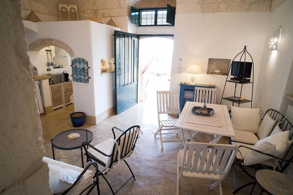 A cozy living area with a dining table, chairs, a TV, and a kitchen in the background.