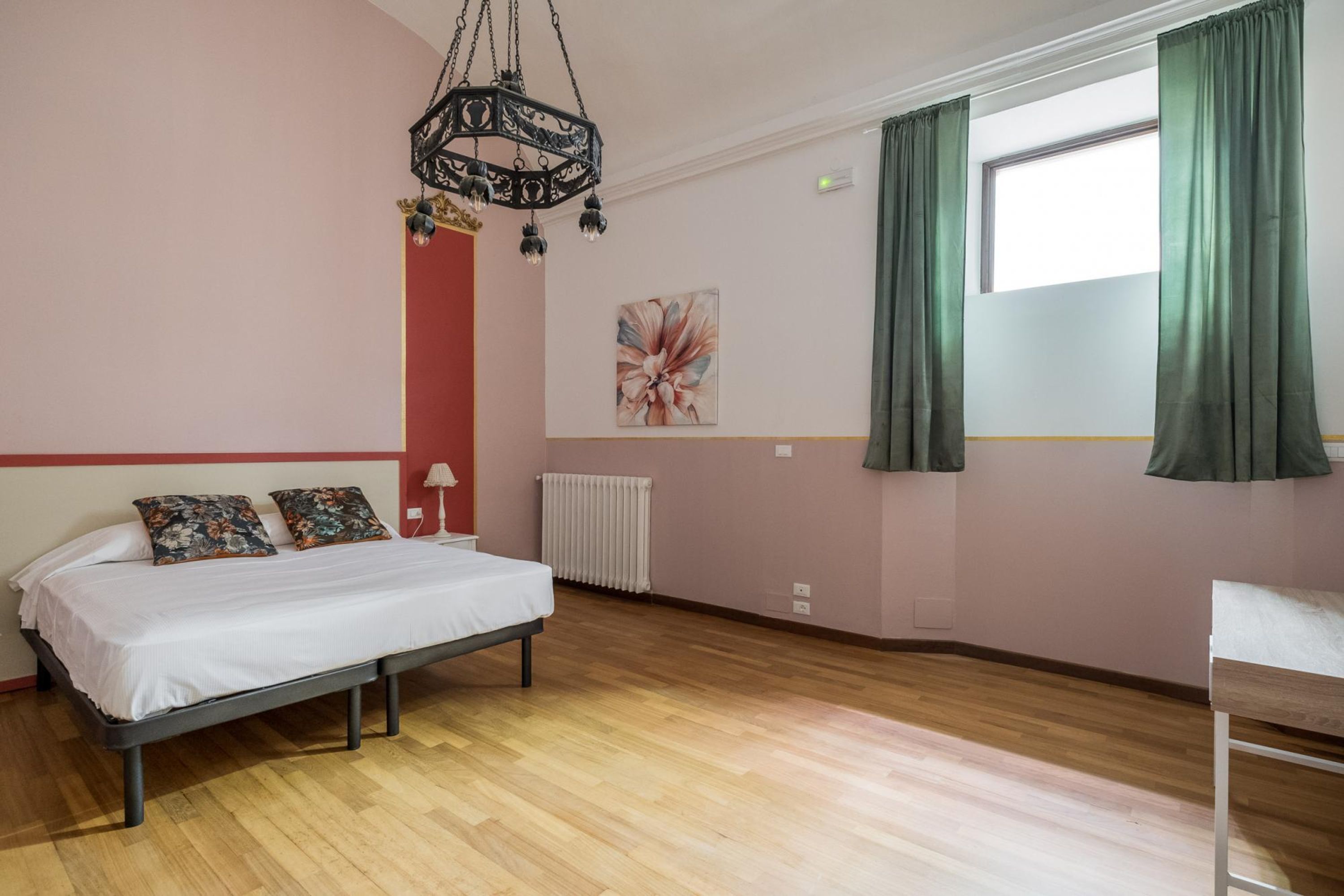 Ein Schlafzimmer mit Bett, Heizkörper, einem Fenster mit Vorhängen und einem Gemälde an der Wand.