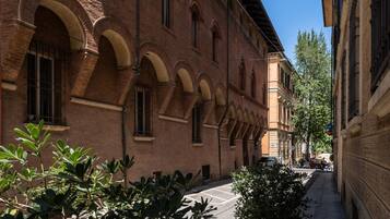 A narrow street with a building featuring arched windows and a brick facade.
