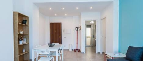 Un espacio de estar moderno con comedor, sofá y cocina al fondo.