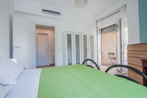 A bedroom with a bed, a wardrobe, and a sliding door leading to a balcony. - Rapisardi 188 Apartment by Wonderful Italy (Catania)