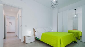 Un dormitorio moderno con cama, mesita de noche y espejo.