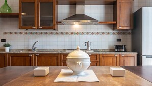 A kitchen with wooden cabinets, a stainless steel range hood, a sink, and a countertop with a coffee maker and a toaster. - Maiorani Family Apartment nel Centro di Napoli (Naples)
