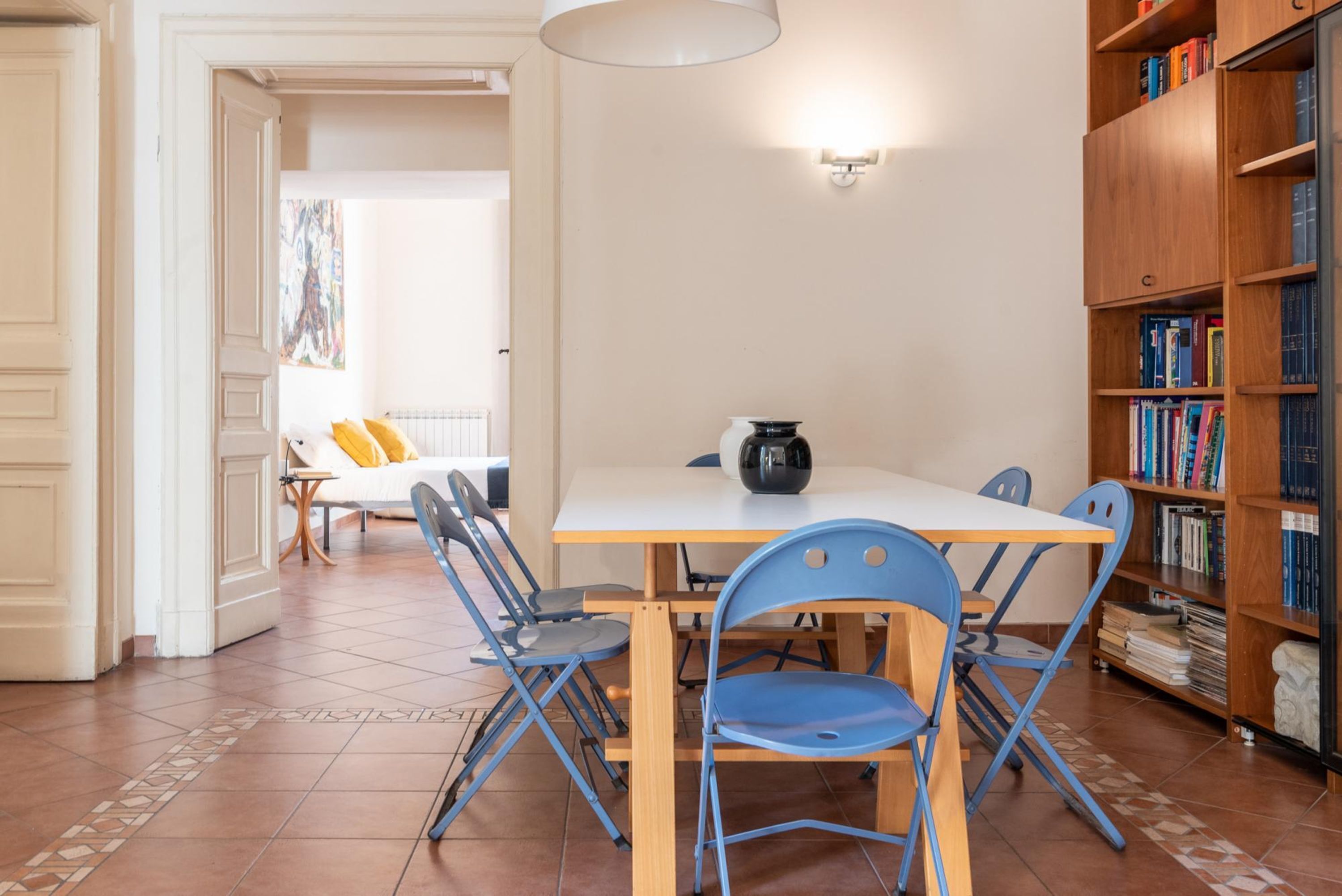 A dining area with a table, chairs, and a bookshelf.