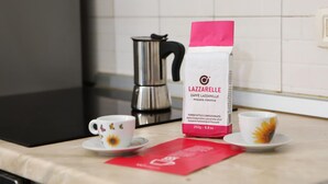 A kitchen counter with a coffee maker, a carton of Lazzarelle coffee, and two cups on saucers. - Napoli Centrale Budget Apartment (Naples)