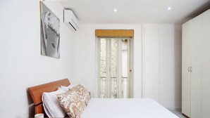 A bedroom with a bed, a nightstand, a wardrobe, and a window with a view of trees. - Napoli Centrale Budget Apartment (Naples)