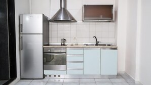 A compact kitchen with a refrigerator, oven, microwave, and a stainless steel range hood. - Napoli Centrale Budget Apartment (Naples)