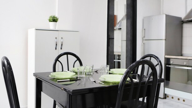 A dining table with four chairs, a white cabinet with glass doors, and a refrigerator in the background. - Napoli Centrale Budget Apartment (Naples)