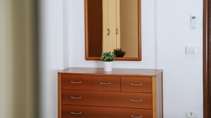 A wooden dresser with a mirror above it and a small potted plant on top. - Napoli Centrale Budget Apartment (Naples)