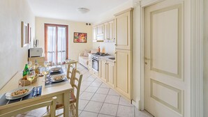 Cucina con zona pranzo, che include un fornello, forno e tavolo apparecchiato con piatti e bicchieri.
