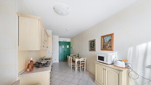 Una cucina compatta con servizi essenziali, una zona pranzo e una porta verde che dà su un'altra stanza.