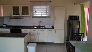 A compact kitchen with white cabinets, a gas stove, a sink, and a microwave.