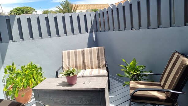 An outdoor patio with two lounge chairs, a small table, and potted plants.