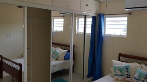 A bedroom with a bed, a wooden chair, a wardrobe, and a window with curtains.