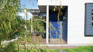 A modern house with a blue door, a covered patio, and a garden area. - Daydream Cottage (Daylesford)