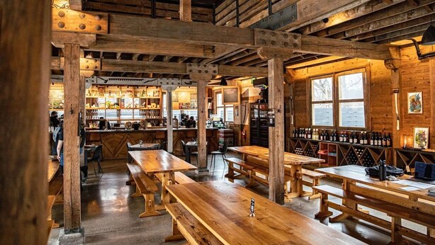 A rustic wooden interior with high ceilings, wooden beams, and a bar area with wine bottles. - Sleeps 20! Fire Pit, Hot Tub & Amazing Location! (Asheville)