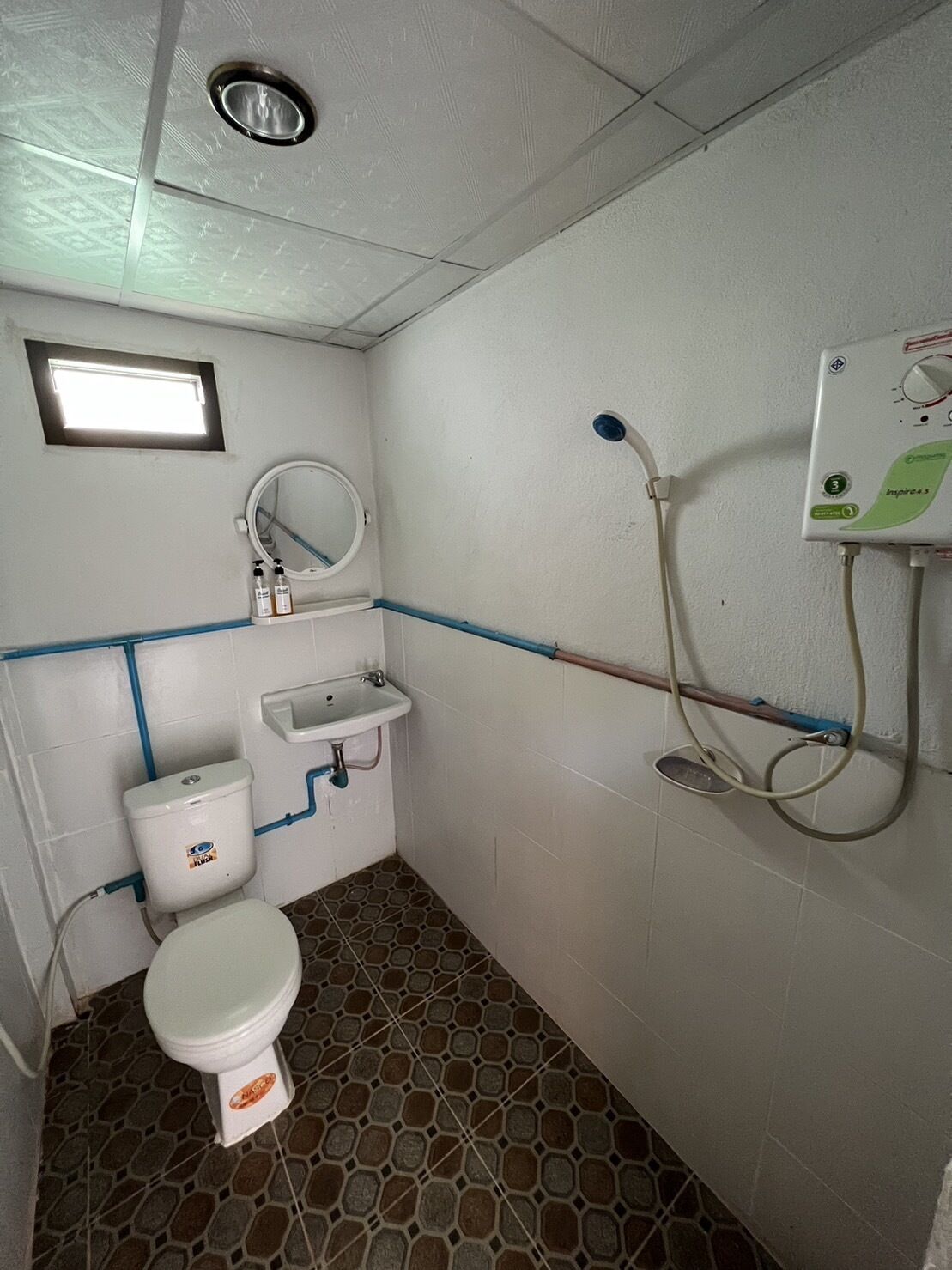 A small bathroom with a toilet, sink, and shower.