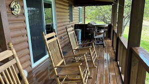 Eine Holzhütte mit Veranda, ausgestattet mit Schaukelstühlen, einem Tisch und einem überdachten Bereich.