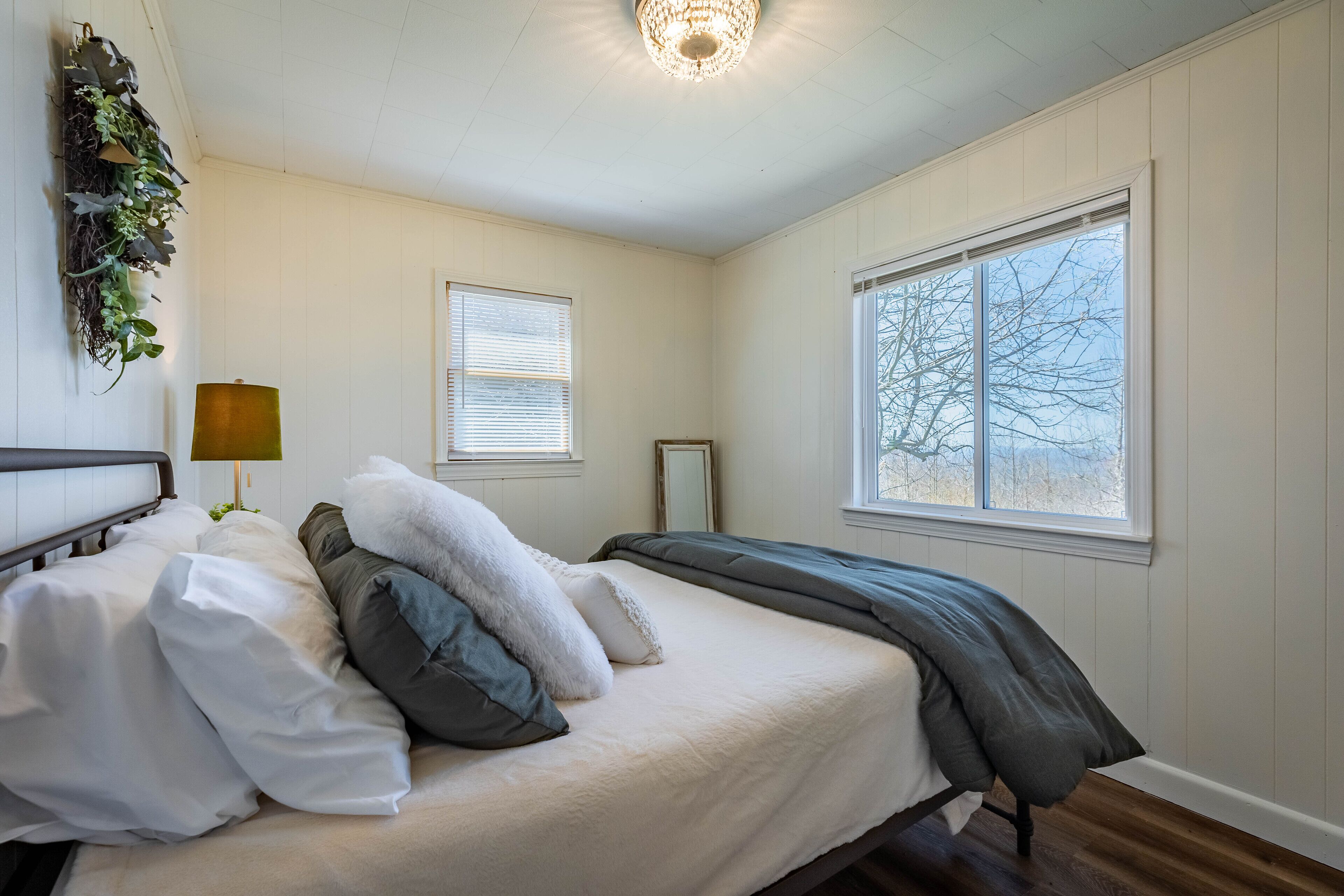 Ein Schlafzimmer mit Bett, Nachttischlampe, Fenster und einer an der Wand befestigten Pflanze.