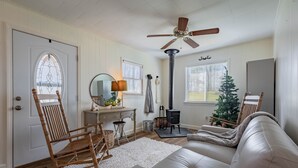Ein gemütliches Wohnzimmer mit Schaukelstuhl, Sofa, Kamin und Deckenventilator.