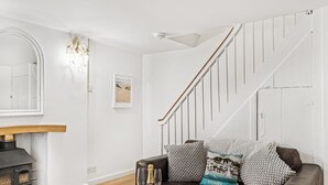 A living room with a fireplace, a sofa with decorative pillows, a wine bottle, and glasses. - Private garden & central location  within 5 min walk of town (Fowey)