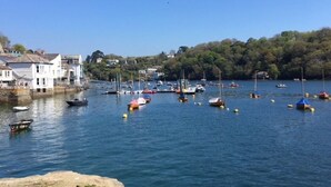 A coastal town with boats docked along the waterfront, buildings on the shore, and a clear blue sky. - Private garden & central location  within 5 min walk of town (Fowey)