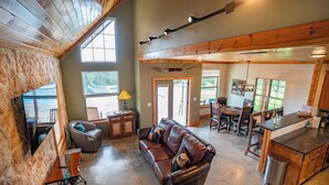 A spacious living area with a large leather sofa, dining table, and kitchen area. - Exquisite Hill Country Cottage-Giraffe and wildlife experiences (Lometa)