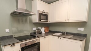 A compact kitchen with a built-in oven, a microwave, and a stovetop. - Silverbirch (Cornhill on Tweed)