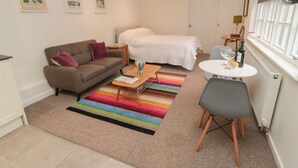 A compact hotel room with a bed, a sofa, a small table, and a TV mounted on the wall. - Silverbirch (Cornhill on Tweed)