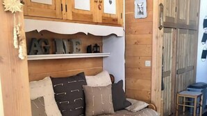 A cozy wooden room with a built-in sofa, wooden cabinets with heart decorations, and a small table. - RDC studio on the slopes, mountain views (Manigod)