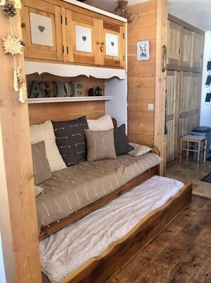 Ein gemütlicher Holzraum mit einer eingebauten Couch, Holzschränken mit Herzverzierungen und einem kleinen Tisch.
