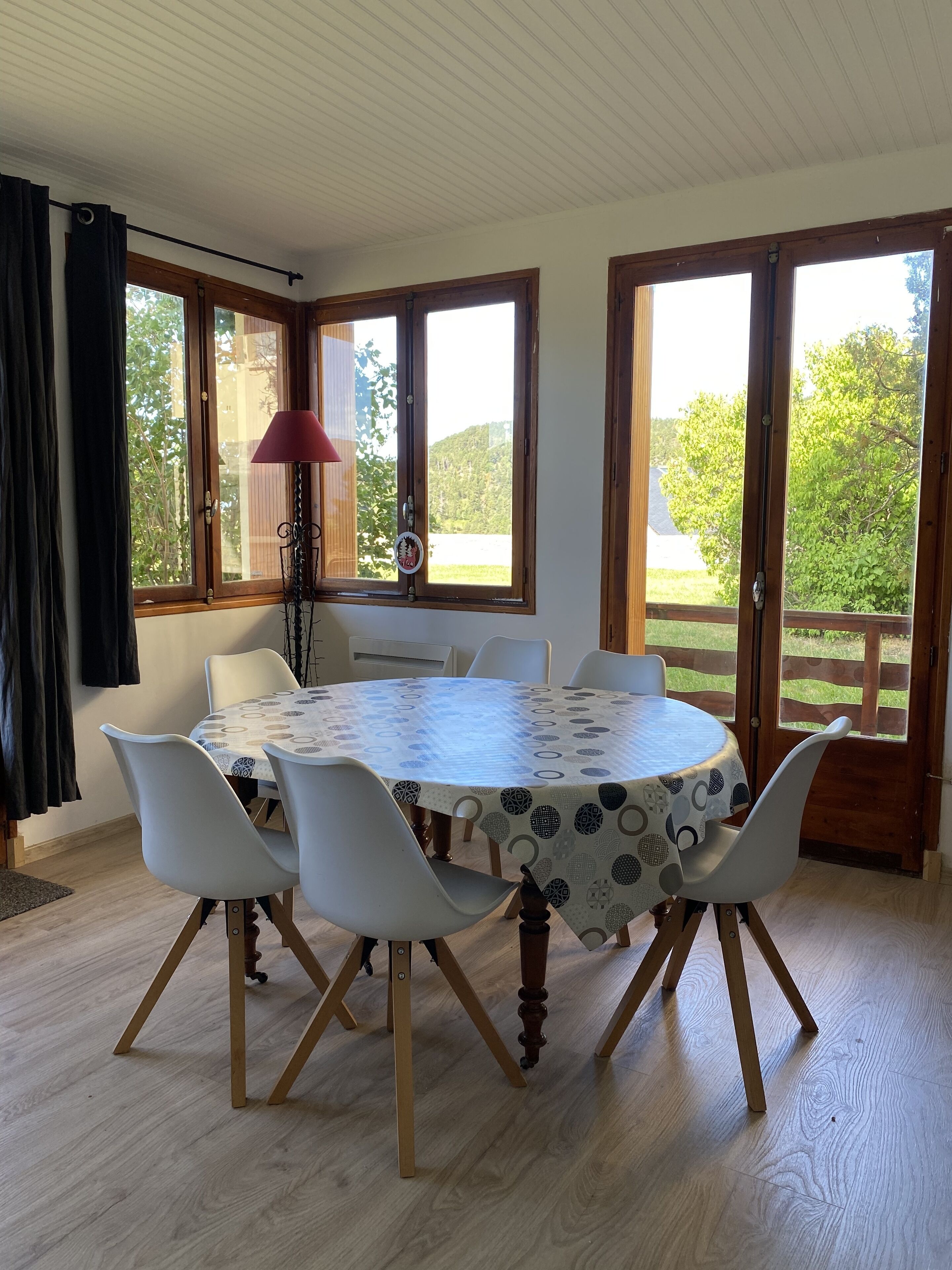 Un coin repas avec une table ronde, des chaises blanches et une nappe à motifs.
