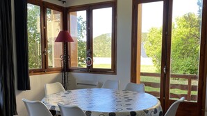 A dining area with a round table, white chairs, and a patterned tablecloth. - Cosy family apartment in the heart of the Pyrenees (Font-Romeu-Odeillo-Via)