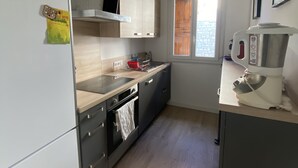 A modern kitchen with a refrigerator, oven, sink, and a coffee maker. - Cosy family apartment in the heart of the Pyrenees (Font-Romeu-Odeillo-Via)