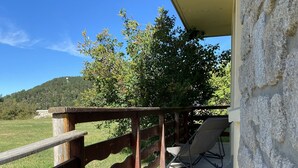 A wooden balcony with a concrete floor, overlooking a grassy field and trees. - Cosy family apartment in the heart of the Pyrenees (Font-Romeu-Odeillo-Via)
