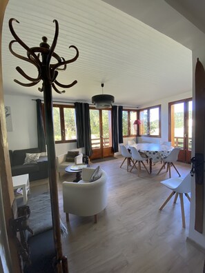 A spacious living room with a dining area, large windows, and a ceiling with a unique design. - Cosy family apartment in the heart of the Pyrenees (Font-Romeu-Odeillo-Via)