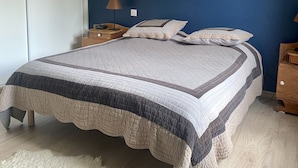 A bedroom with a large bed, two bedside tables, a nightstand, a fluffy rug, and a blue accent wall. - Cosy family apartment in the heart of the Pyrenees (Font-Romeu-Odeillo-Via)