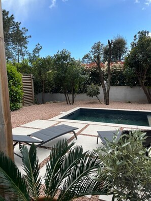 A backyard with a swimming pool, two lounge chairs, and various plants. - Contemporary villa for 2 people, private pool, enclosed grounds  (San-Gavino-Di-Carbini)