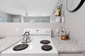 A kitchen with a white stove, a kettle, and a knife block on the counter. - Nov Dates Open-Pet friendly near Chatt hospital (Chattanooga)
