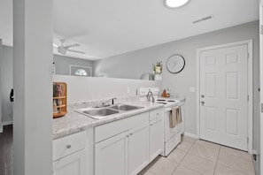 A modern kitchen with white cabinetry, a double sink, a stove, and a clock on the wall. - Nov Dates Open-Pet friendly near Chatt hospital (Chattanooga)