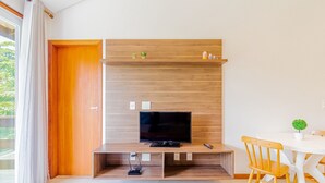 Ein modernes Wohnzimmer mit einem Holz-Fernsehschrank, einem Esstisch mit Stühlen und einer kleinen Pflanze.