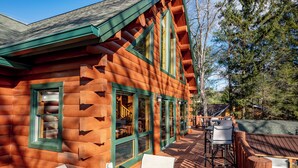 A log cabin with a deck, outdoor seating, and a hot tub. - Stylish Lakefront Escape w/ Hot Tub, Bar & Dock (Oakland)