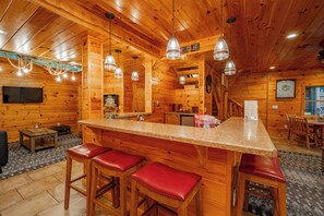 A wooden cabin interior with a bar area, wooden walls, and a television. - Stylish Lakefront Escape w/ Hot Tub, Bar & Dock (Oakland)