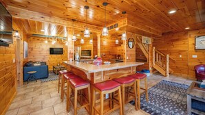 A wooden interior with a bar area, stools, a sofa, and a staircase. - Stylish Lakefront Escape w/ Hot Tub, Bar & Dock (Oakland)