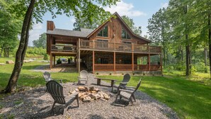 A large log cabin with a balcony, outdoor seating, and a fire pit. - Woodsy Retreat Near Wisp w/ Golf & Hot Tub (McHenry)